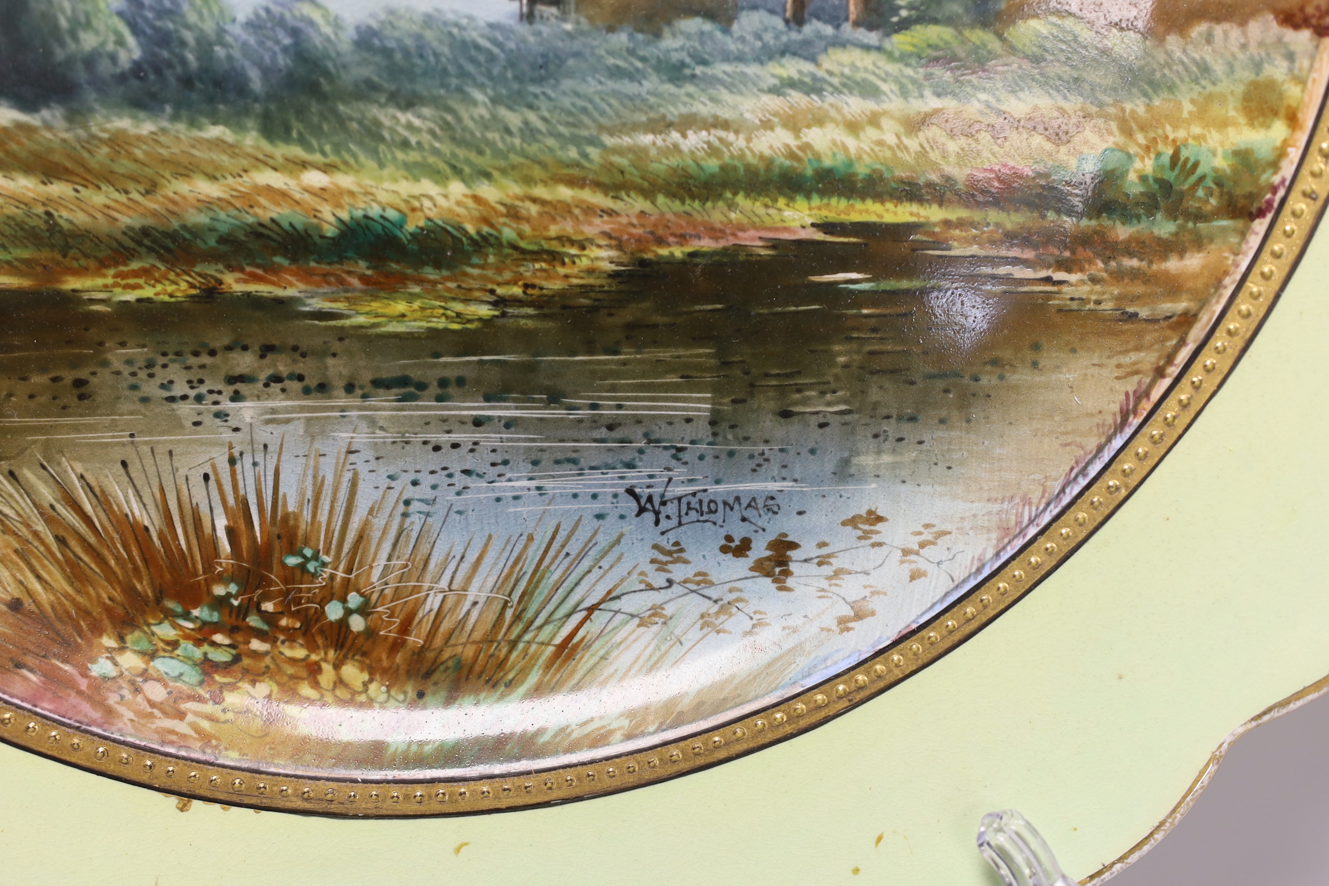 A mid 19th century English pottery charger painted with a coastal landscape under a light green border signed W. Thomas, indistinct factory and registration mark 39cm in diameter